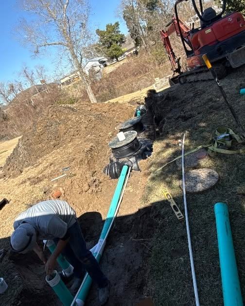 Two crew members plumbing the inlet and outlet on a freshly set tank.