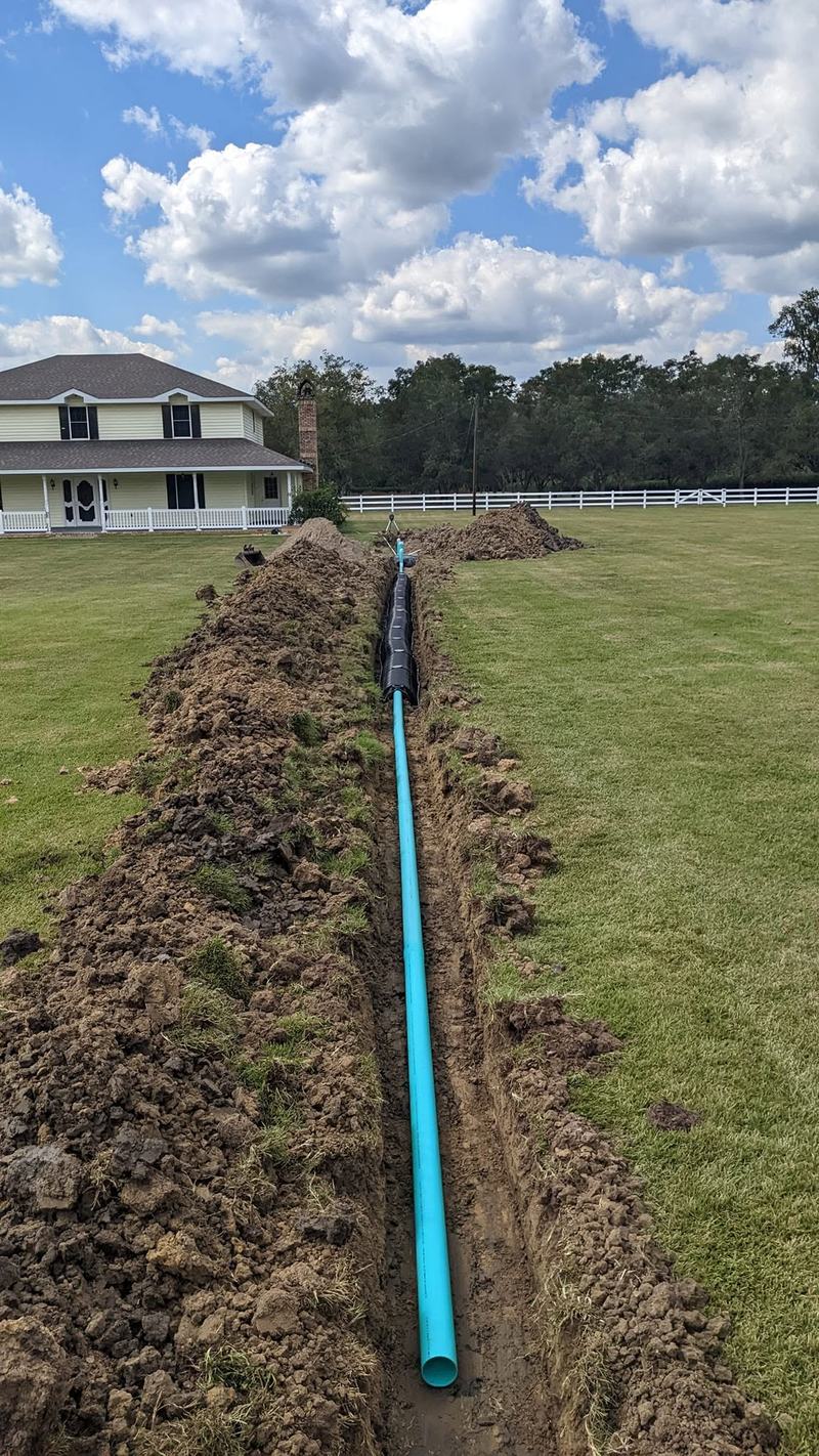 A discharge line laid in an open trench running away from the house.
