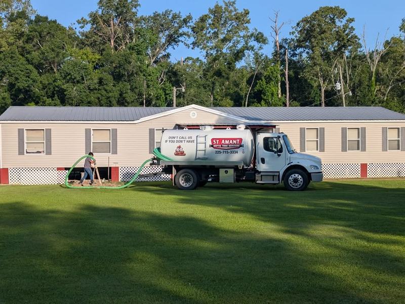 A pump-out under way at a mobile home, hoses run across the lawn.