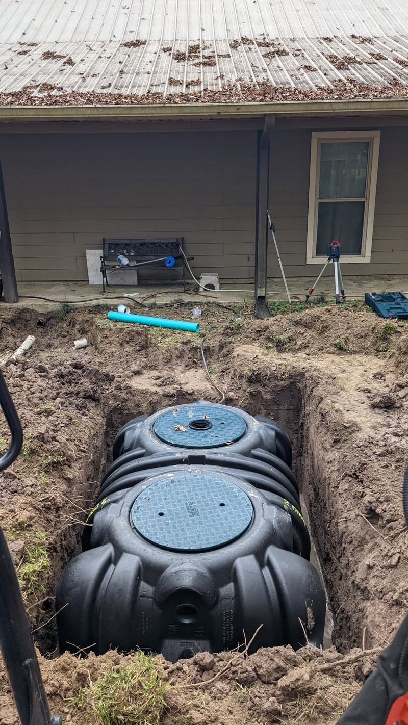 A new treatment tank set in its excavation beside a home.