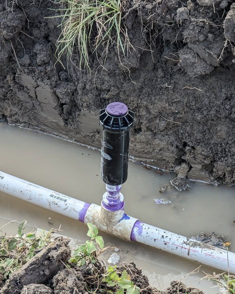 A freshly solvent-welded fitting on a line uncovered in a trench.