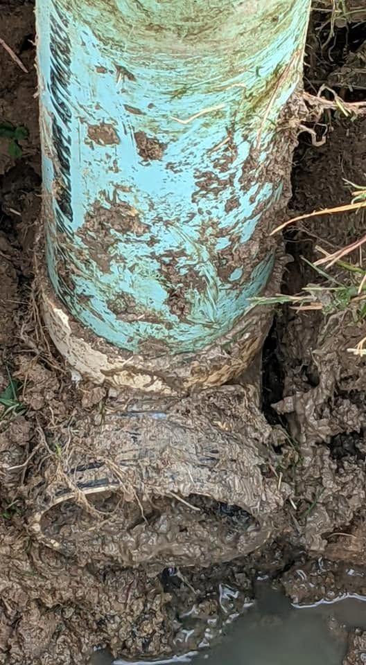 A pipe uncovered in a wet trench during a line trace.