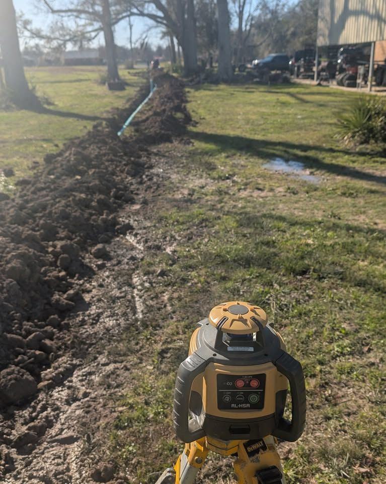 A laser level set up in an open trench to hold the grade.