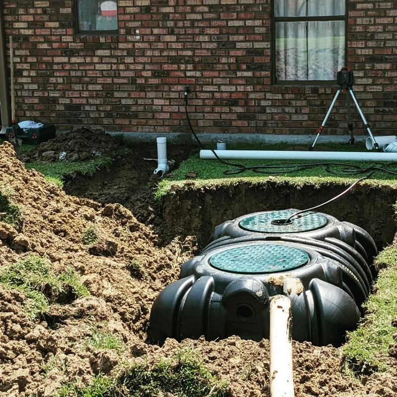 A treatment tank set and plumbed beside a brick house.