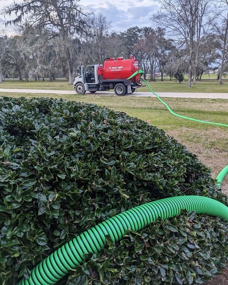 A suction hose run over a hedge to the pump truck waiting at the roadside.