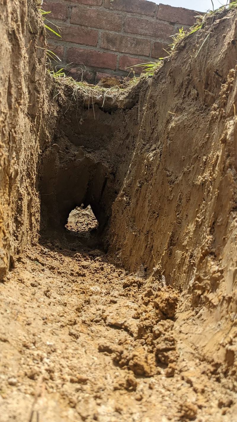 An excavation opened up alongside a brick wall to reach a failed line.