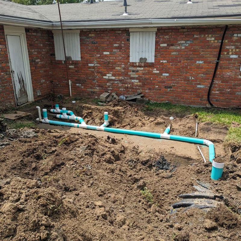 A new pipe manifold plumbed in beside a brick house.
